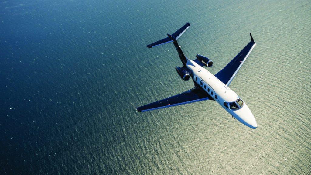 Embraer Phenom business jet in flight over open water